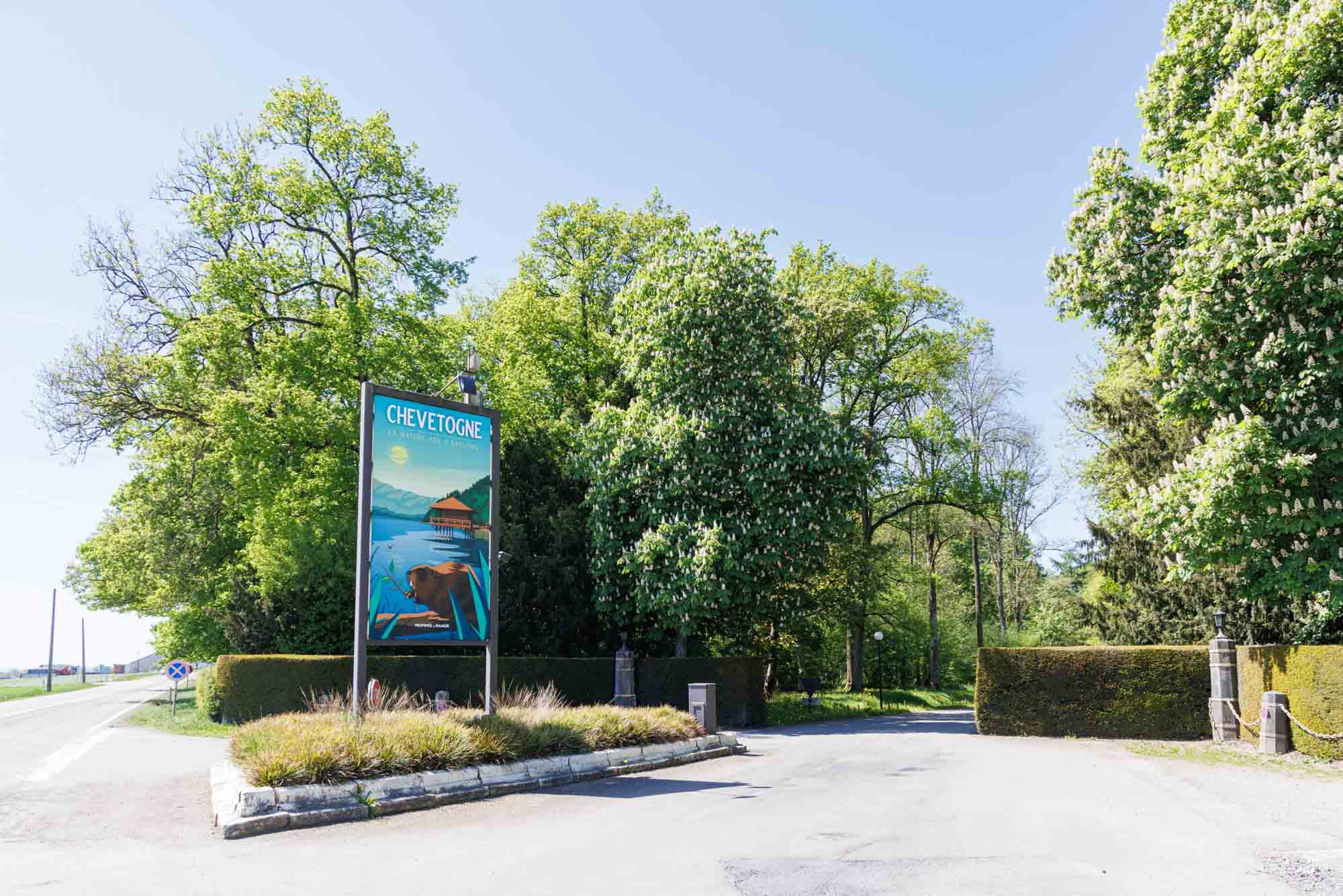 Bord en toegang tot het domein van Chevetogne, omringd door bomen en groene hagen.