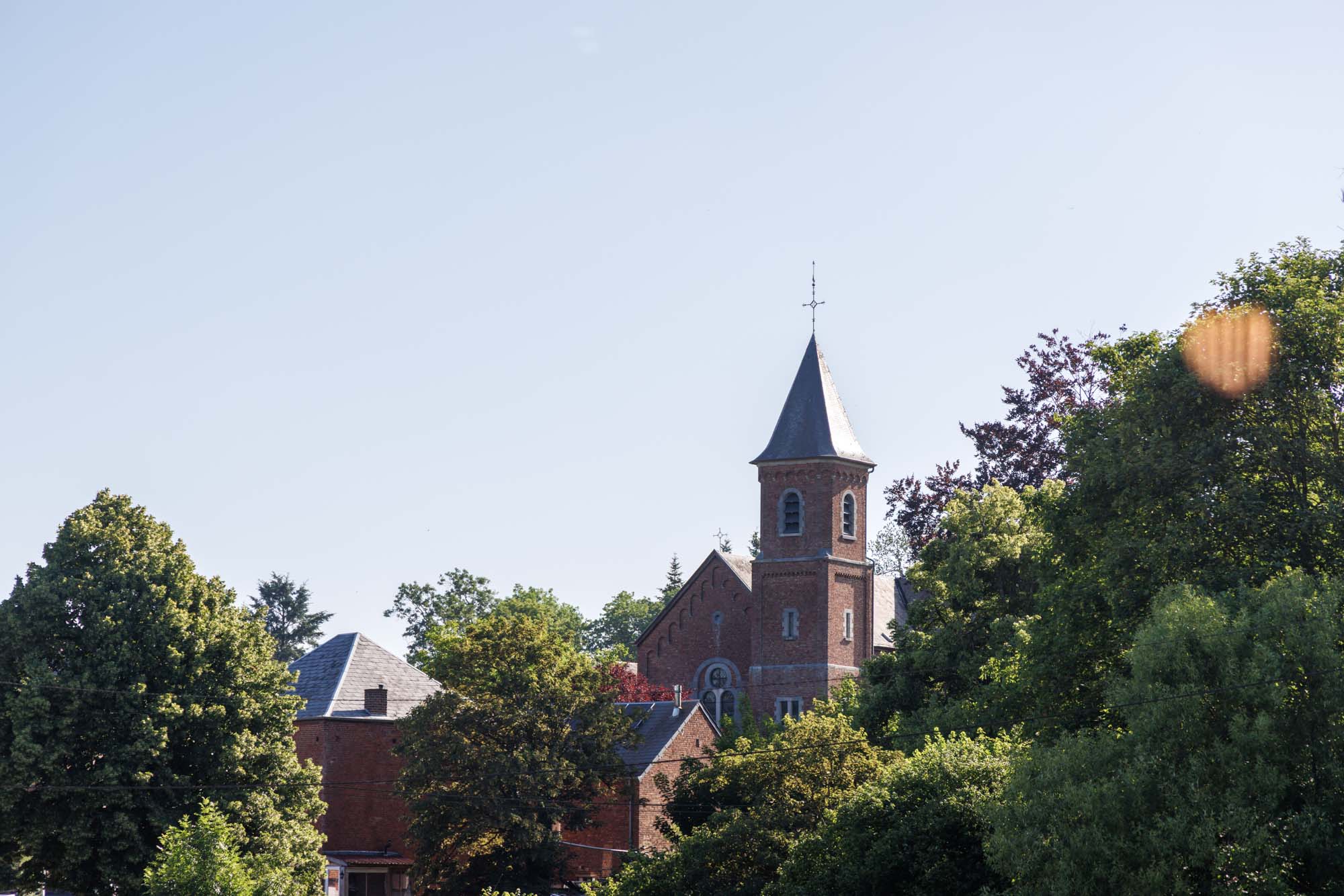 Église de Wanlin entourée d’arbres sous un ciel bleu