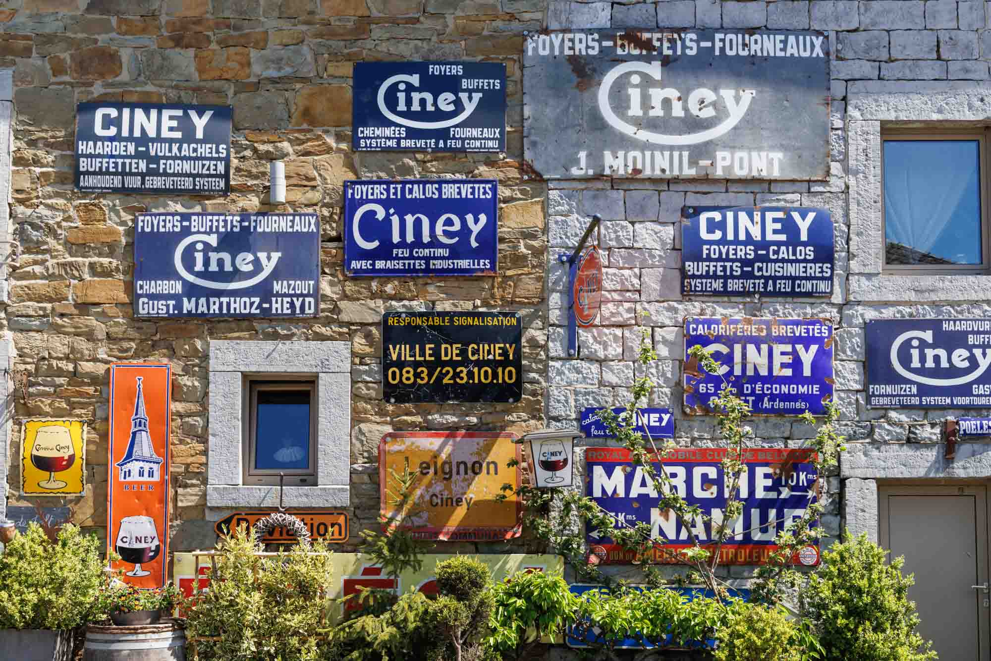Oude reclameborden van Ciney op een stenen muur, lokaal stedelijk erfgoed.