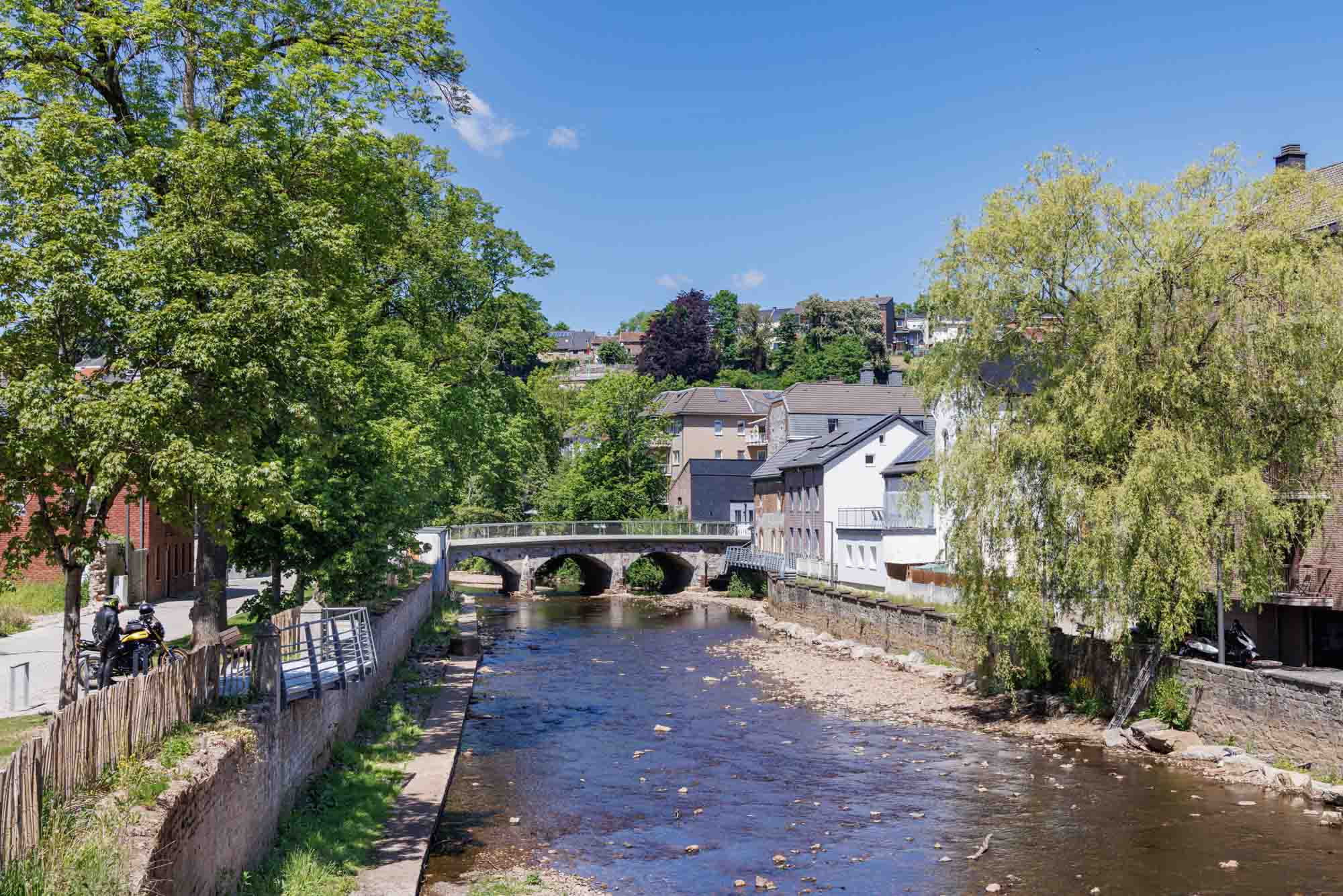La Vesdre à Eupen, avec un pont en pierre, des maisons riveraines et une végétation estivale.